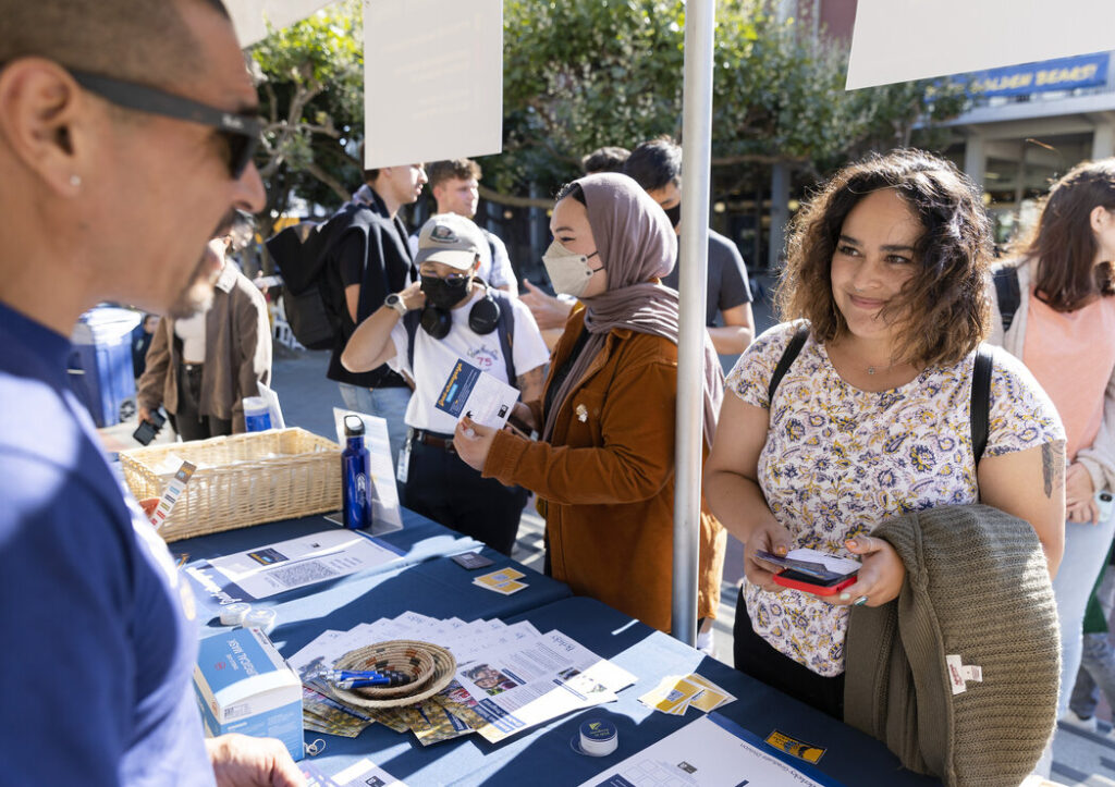 student receiving information from staff member at booth