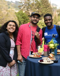 three students pose in a huddle at the outdoor Graduate Diversity Reception in September 2021