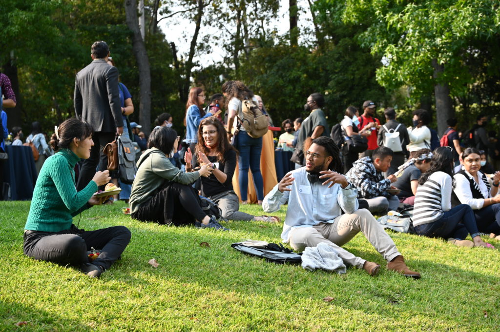 Students sit and talk on grass at an outdoor Graduate Diversity Reception, Sept. 2, 2021