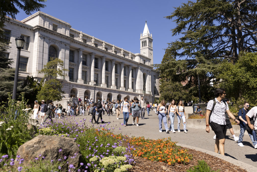 students walking on campus with the campanile in the background