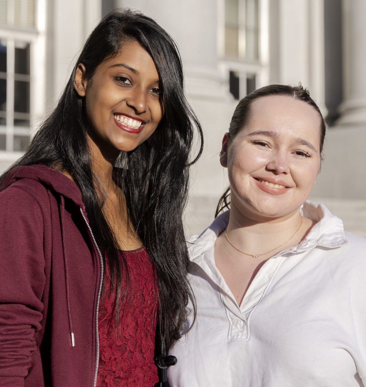 Two female students smiling and standing in front of Sproul Hall