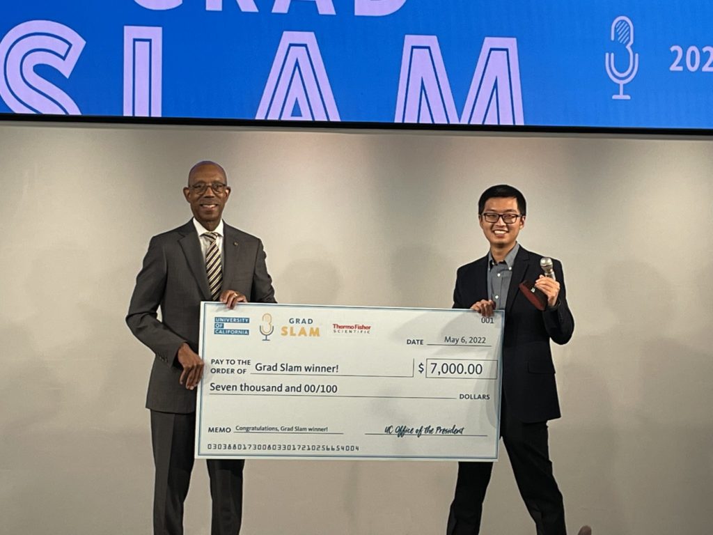 berkeley phd student poses with uc president drake with large check