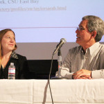 two people sitting at a table in front of a microphone.