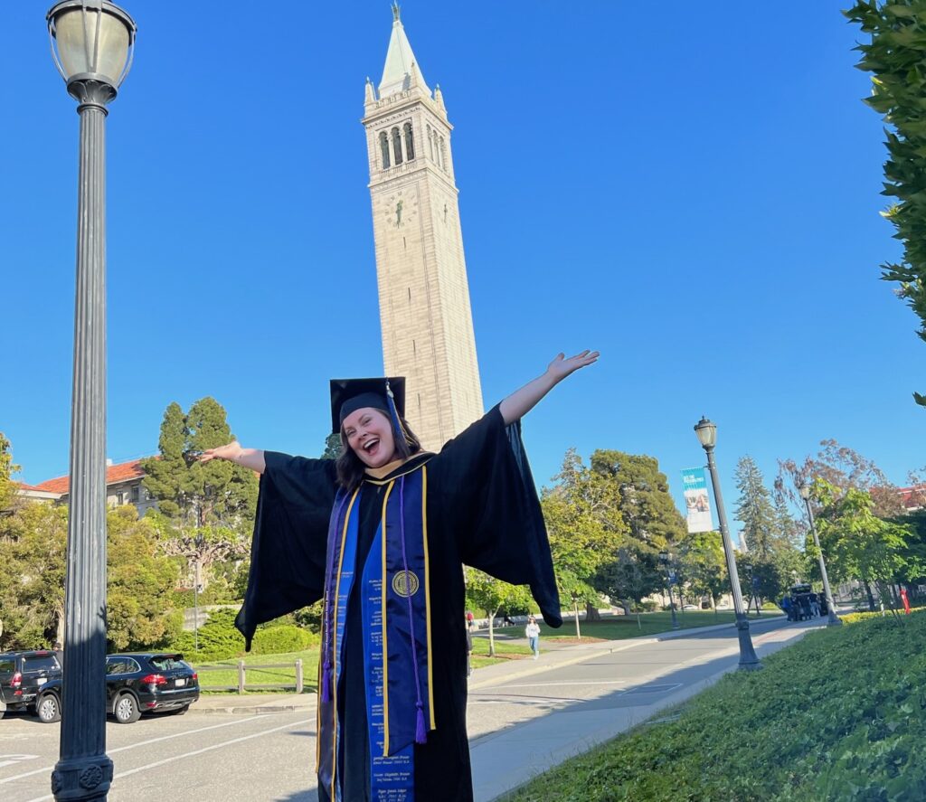 Sarah Lance in graduate gown standing in front of Campanile