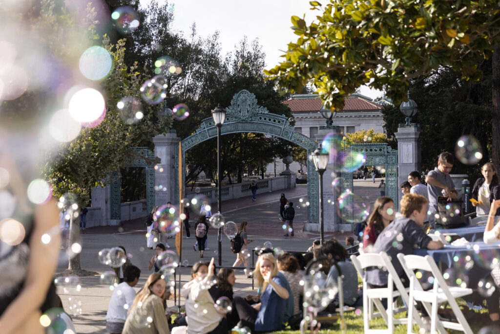 students and bubbles in the foreground with sather gate in the background