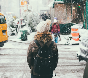 women walking down city street while it snows