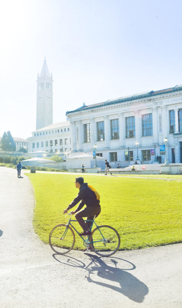 student biking in the foreground with campanile in the background