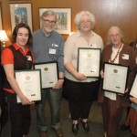 Four mentoring award winners pose with plaque