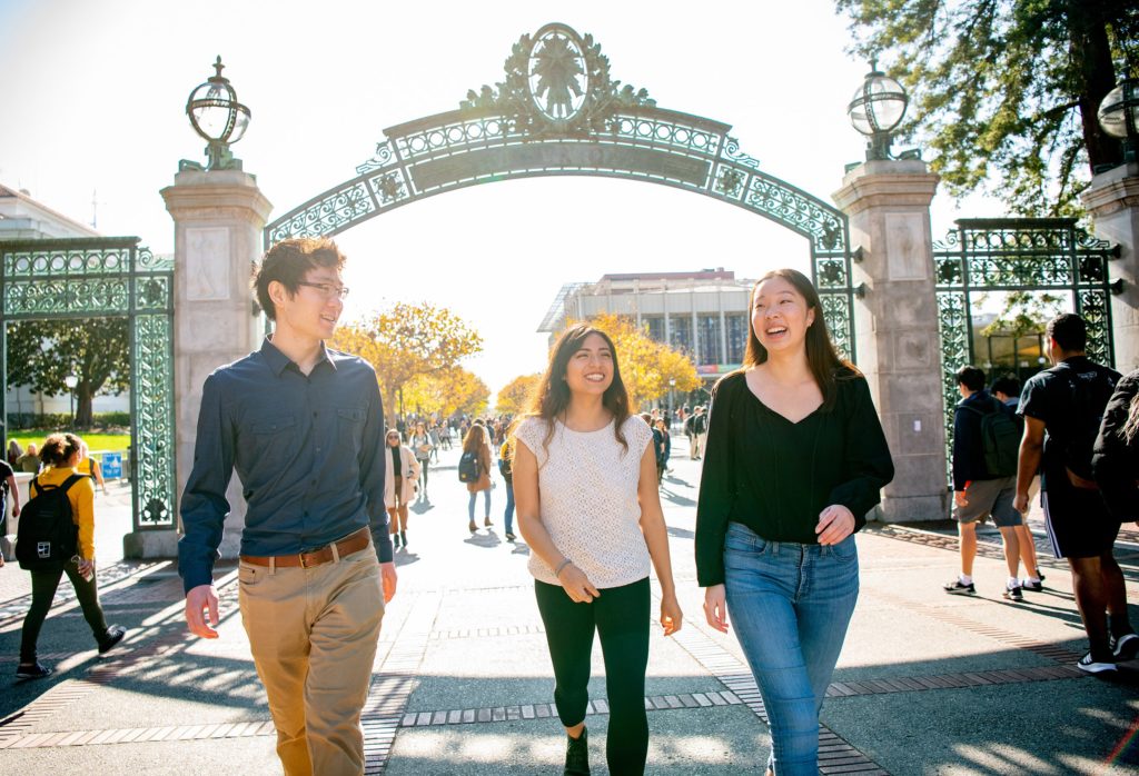 Three students walking under Sather Gate
