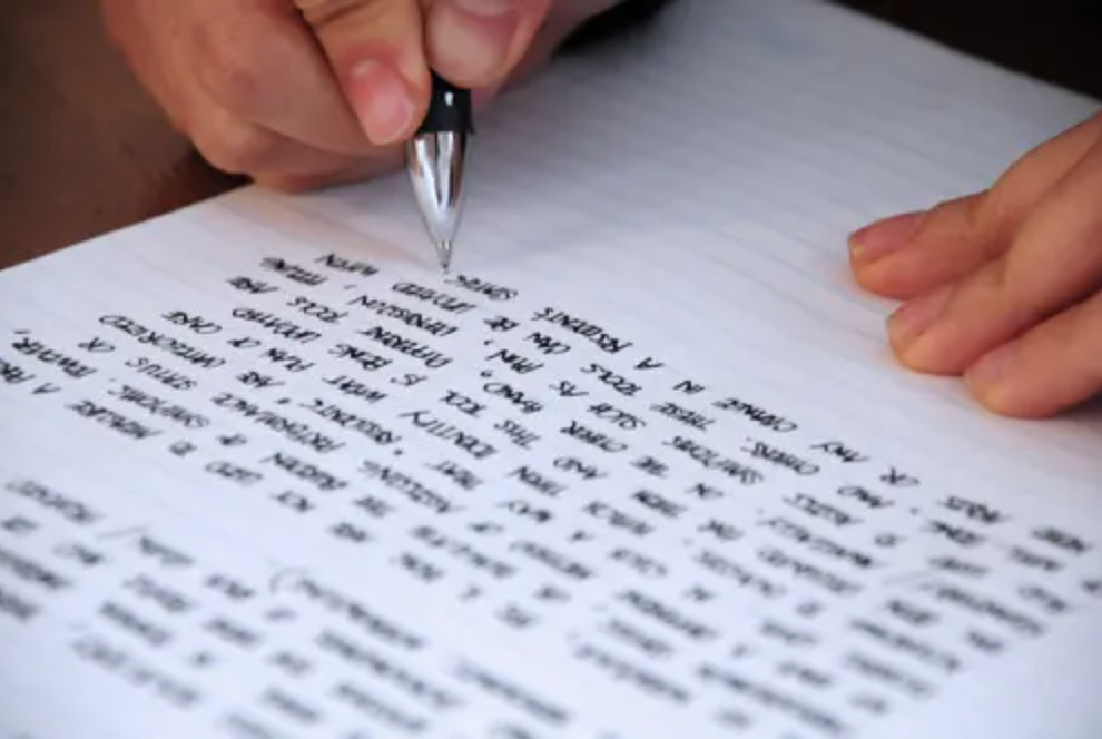 Writing a long essay on a piece of paper.