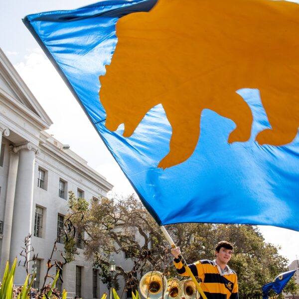 Student waving flag with Cali Golden Bear on it