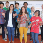 Photo of 8 engineering students holding prototypes.